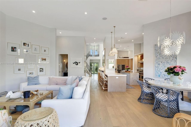 living area with light wood finished floors, recessed lighting, and a towering ceiling