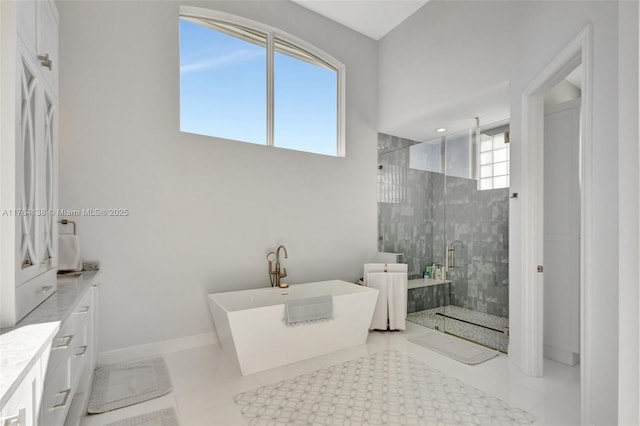 bathroom with tile patterned floors, a soaking tub, baseboards, and tiled shower