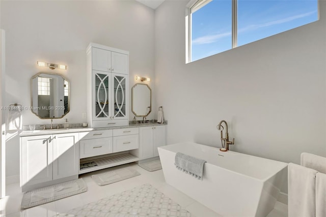 bathroom featuring double vanity, a freestanding bath, and a sink