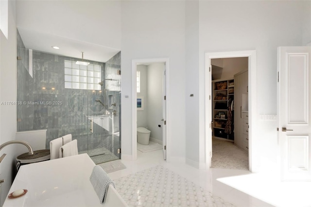 bathroom featuring baseboards, a stall shower, tile patterned flooring, a spacious closet, and toilet