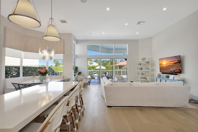 living area featuring visible vents, recessed lighting, a towering ceiling, and wood finished floors