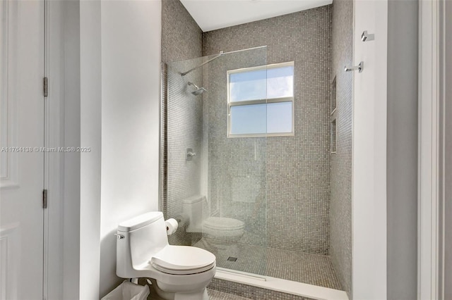 bathroom featuring tiled shower and toilet