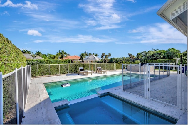 view of pool featuring a patio area, fence, and a pool with connected hot tub