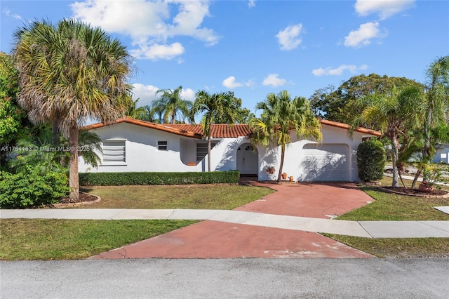 mediterranean / spanish-style home with stucco siding, a garage, a front lawn, and a tiled roof