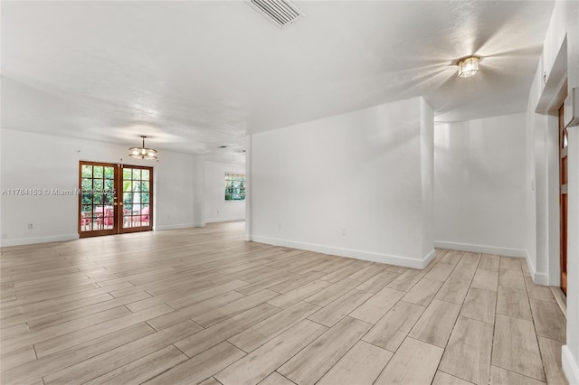 spare room featuring visible vents, baseboards, light wood-style floors, and an inviting chandelier