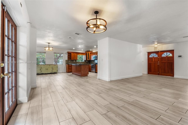 interior space featuring dark countertops, backsplash, open floor plan, a notable chandelier, and stainless steel appliances