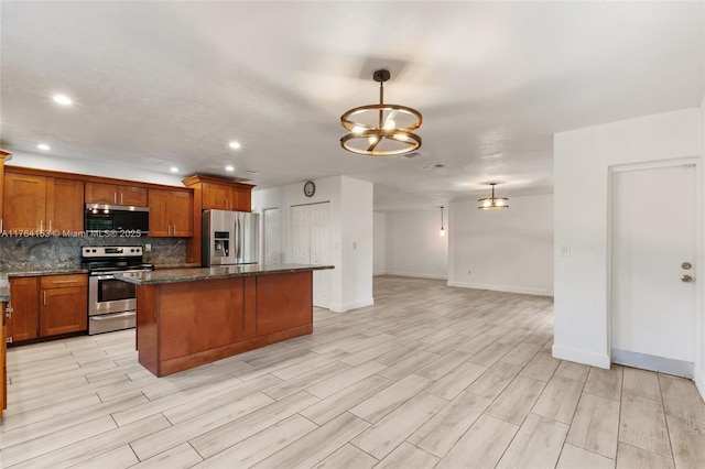 kitchen featuring brown cabinets, tasteful backsplash, a center island, stainless steel appliances, and an inviting chandelier