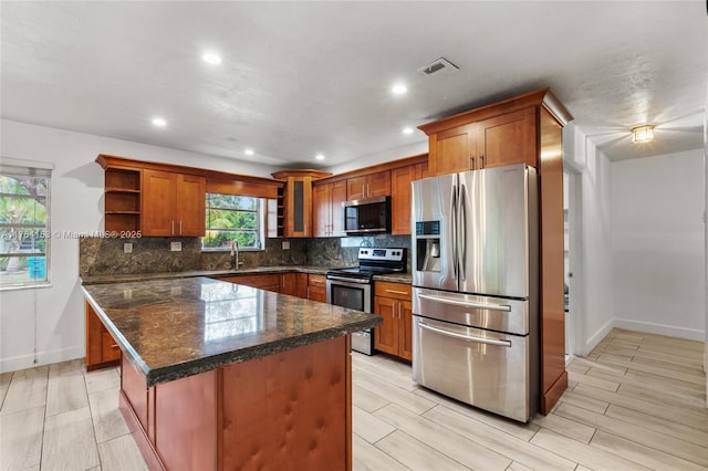 kitchen featuring visible vents, open shelves, a sink, stainless steel appliances, and tasteful backsplash