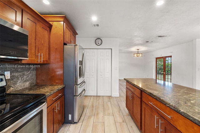 kitchen with visible vents, decorative backsplash, dark stone countertops, brown cabinets, and appliances with stainless steel finishes