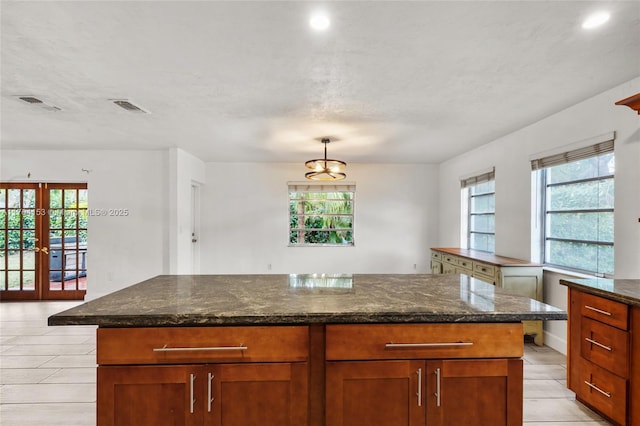 kitchen with dark stone countertops, plenty of natural light, and visible vents