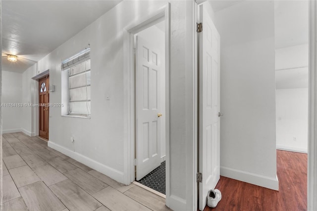 hallway featuring baseboards and wood finished floors