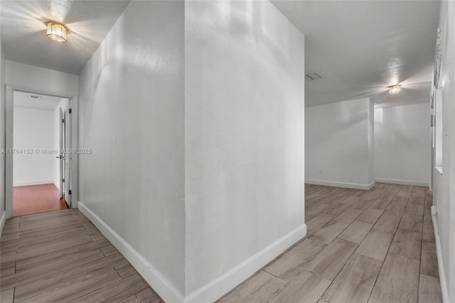 corridor featuring wood finish floors, visible vents, and baseboards