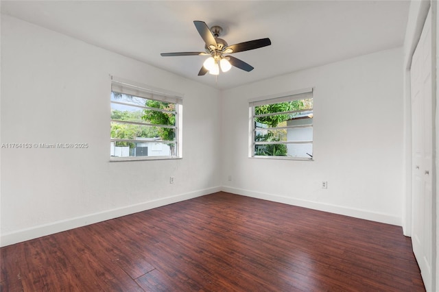 spare room featuring baseboards, a healthy amount of sunlight, wood finished floors, and a ceiling fan