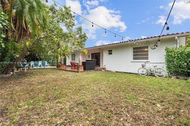 back of property featuring a yard, central AC unit, a patio, and stucco siding