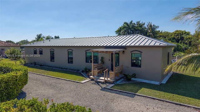 view of front of house featuring stucco siding, metal roof, a front yard, and a standing seam roof