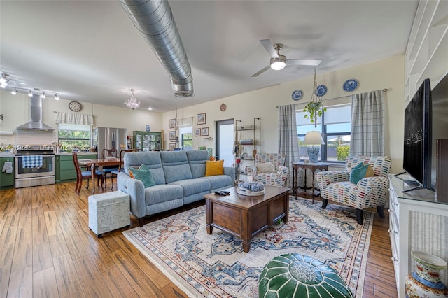 living area featuring ceiling fan with notable chandelier and wood-type flooring