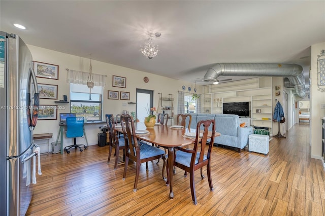 dining room with light wood-type flooring and an inviting chandelier