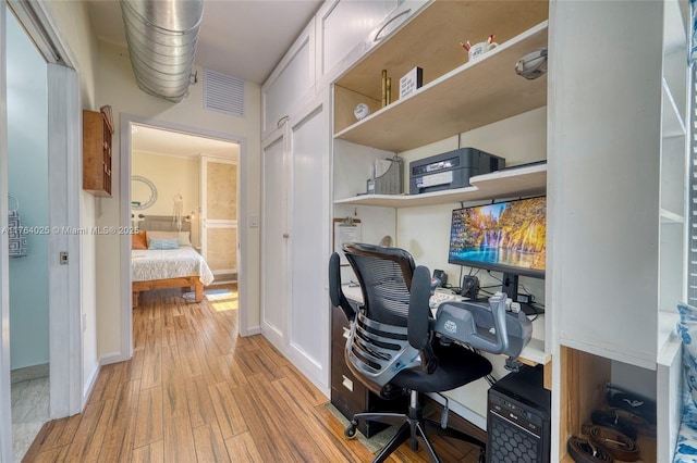 office featuring light wood-style flooring, baseboards, visible vents, and built in desk