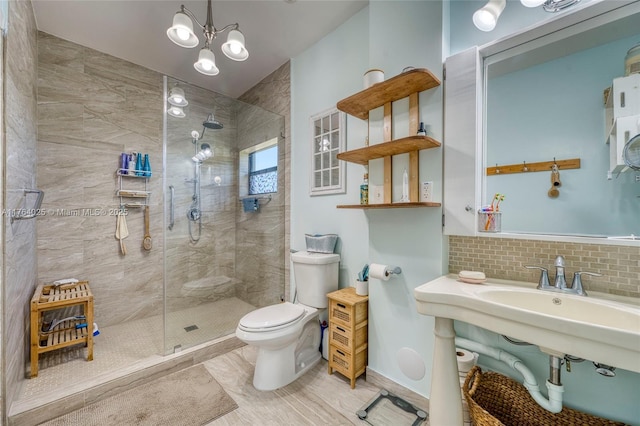 full bath with tasteful backsplash, toilet, tiled shower, and an inviting chandelier