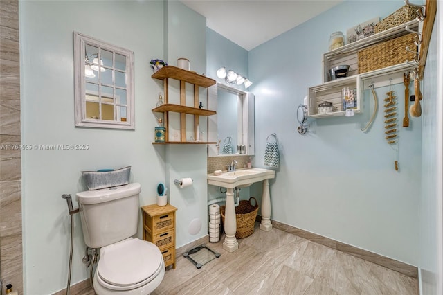 bathroom with tasteful backsplash, toilet, and baseboards