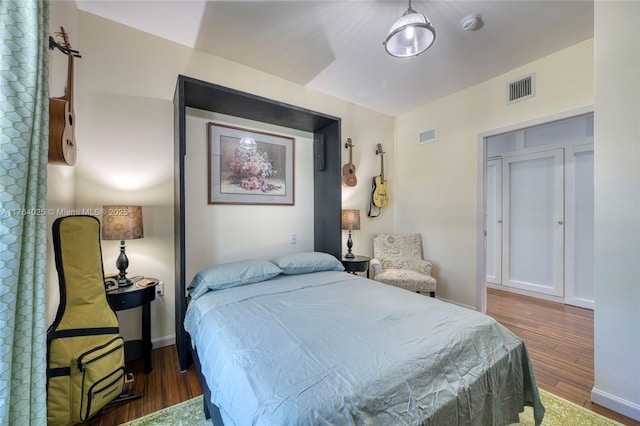 bedroom featuring visible vents, baseboards, and wood finished floors