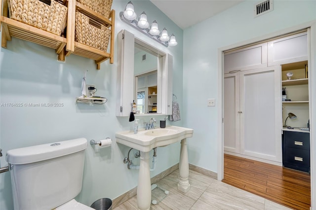 half bath featuring visible vents, baseboards, toilet, and wood finished floors