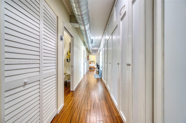 corridor featuring baseboards and hardwood / wood-style floors