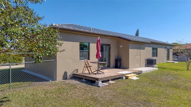 back of property with stucco siding, a lawn, a deck, fence, and metal roof