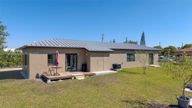 back of house with fence, stucco siding, french doors, a lawn, and a standing seam roof