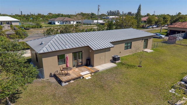 rear view of property with a standing seam roof, a lawn, fence, and stucco siding