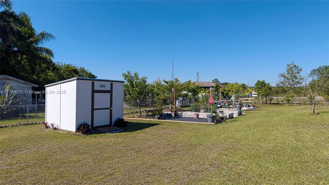 view of yard featuring a storage shed, fence, and an outdoor structure