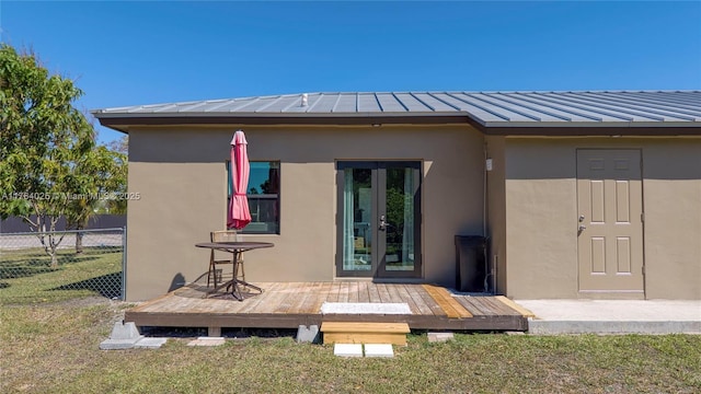 back of property with stucco siding, a lawn, a deck, and fence