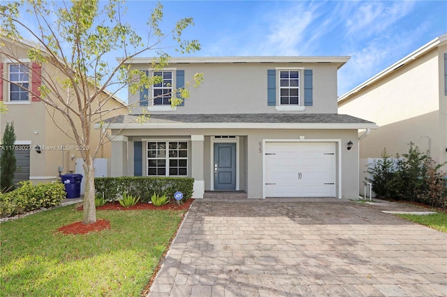 traditional-style home featuring stucco siding, a front lawn, decorative driveway, and a garage