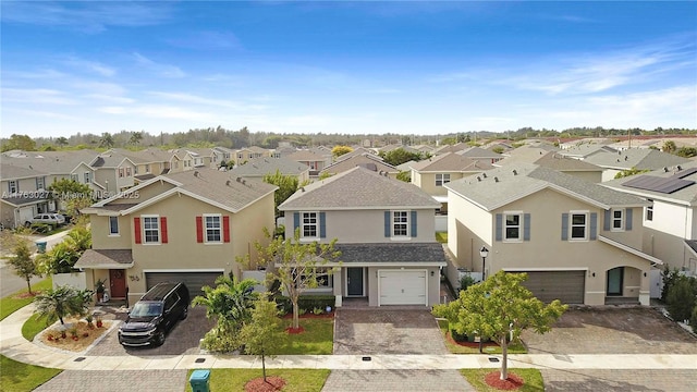 traditional home with stucco siding, a residential view, an attached garage, and decorative driveway