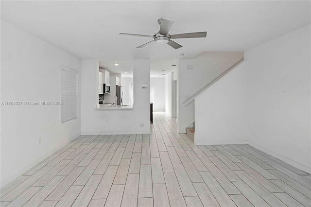 unfurnished living room with stairway, light wood-style floors, and ceiling fan