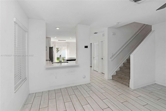 interior space featuring a sink, stairway, wood finish floors, and baseboards