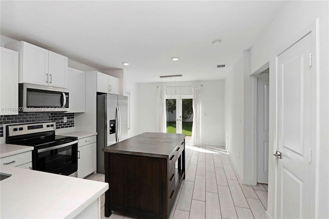 kitchen featuring visible vents, backsplash, a center island, french doors, and stainless steel appliances