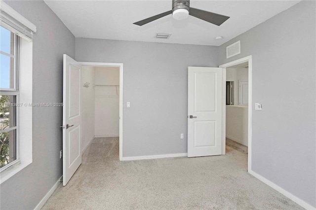 unfurnished bedroom featuring a walk in closet, carpet, and visible vents