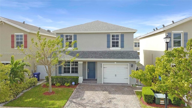 traditional-style house with stucco siding, an attached garage, a shingled roof, and decorative driveway