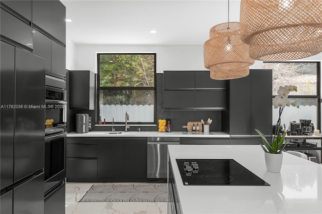 kitchen featuring light countertops, appliances with stainless steel finishes, marble finish floor, modern cabinets, and a sink