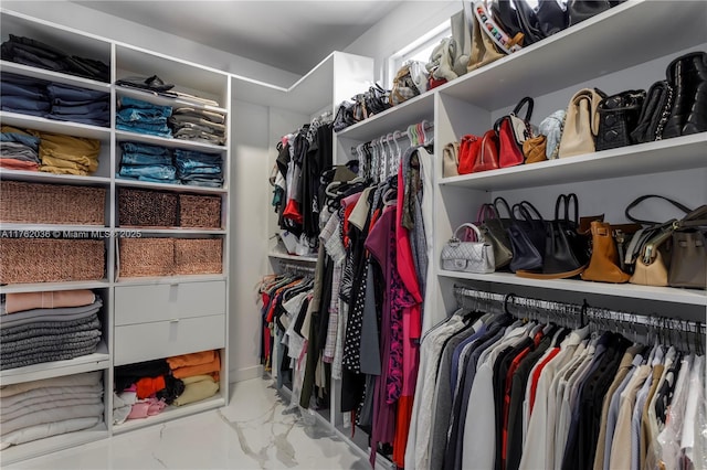 walk in closet featuring marble finish floor