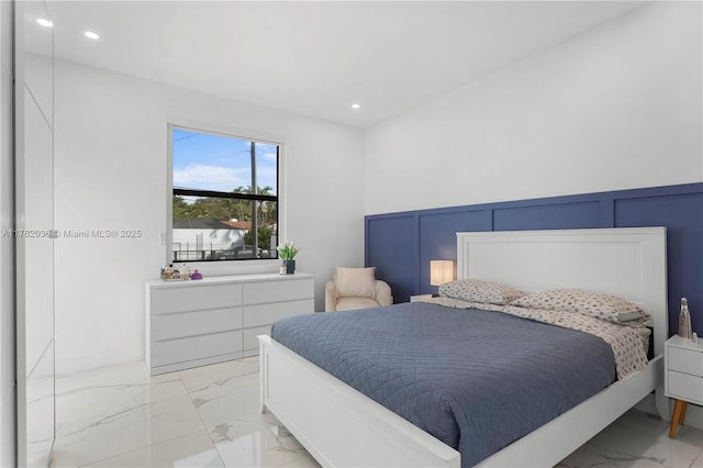 bedroom featuring recessed lighting, a decorative wall, marble finish floor, and a wainscoted wall