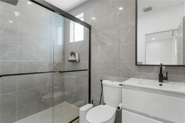 bathroom featuring vanity, visible vents, a stall shower, tile walls, and toilet