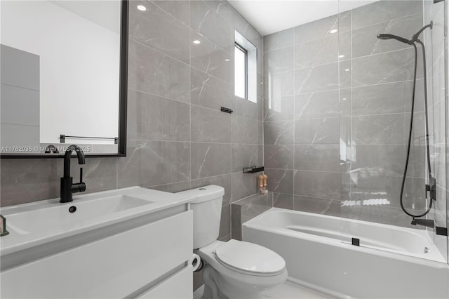 full bathroom featuring toilet, vanity, tile walls, and bathing tub / shower combination