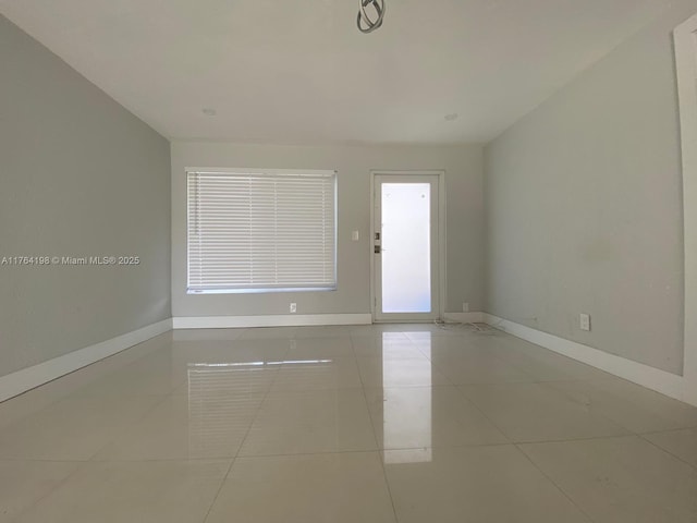 unfurnished room with light tile patterned floors and baseboards