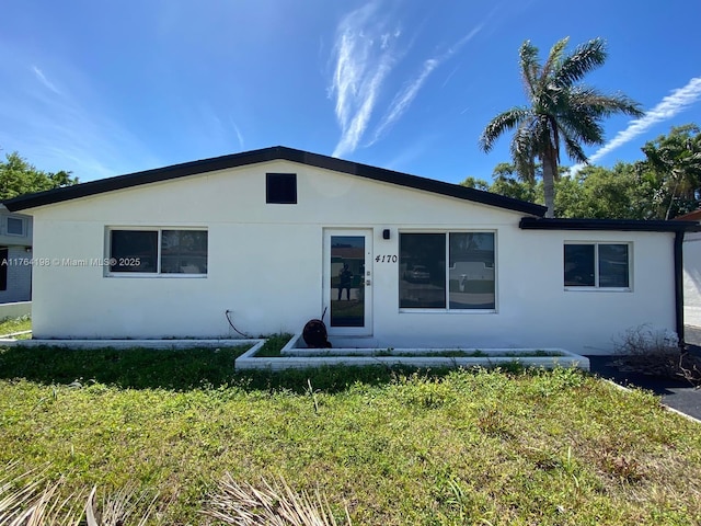 view of front of house with stucco siding and a front yard