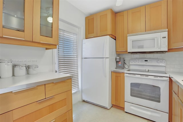 kitchen featuring backsplash, light brown cabinets, glass insert cabinets, light countertops, and white appliances