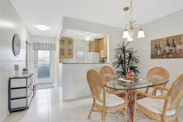 dining area with light tile patterned flooring, ceiling fan with notable chandelier, and baseboards