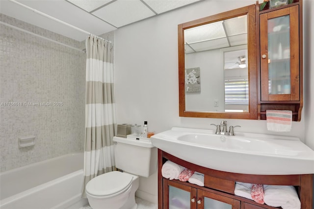 bathroom featuring shower / bathtub combination with curtain, toilet, a ceiling fan, a paneled ceiling, and vanity