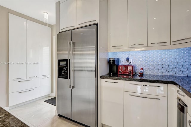 kitchen featuring dark stone counters, decorative backsplash, white cabinets, high end refrigerator, and modern cabinets